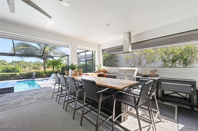 view of patio with area for grilling, a lanai, exterior bar, and grilling area