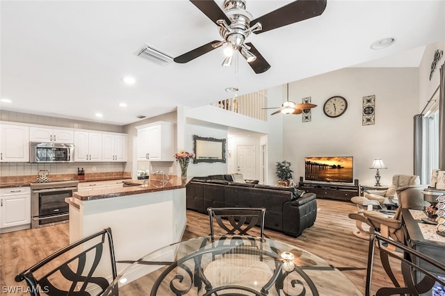 interior space with ceiling fan, vaulted ceiling, and light wood-type flooring