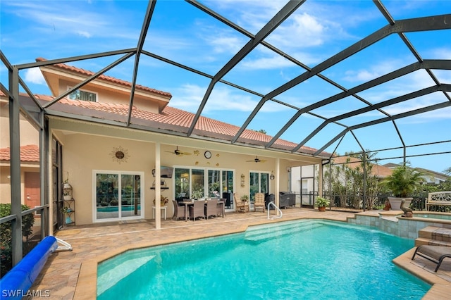 back of property featuring glass enclosure, ceiling fan, and a patio area