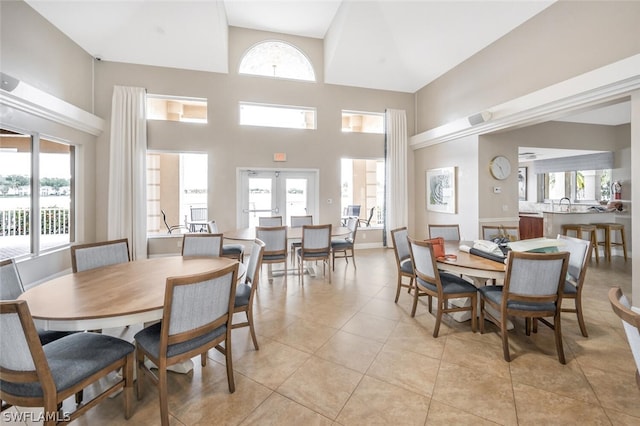 tiled dining space with a towering ceiling and french doors