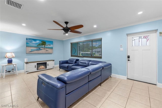 living room with ceiling fan, a fireplace, light tile patterned floors, and crown molding