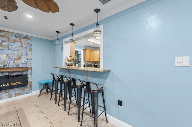 kitchen with pendant lighting, crown molding, ceiling fan, a fireplace, and a kitchen bar