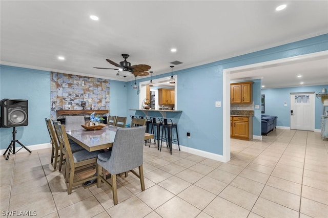 tiled dining area with ceiling fan and crown molding