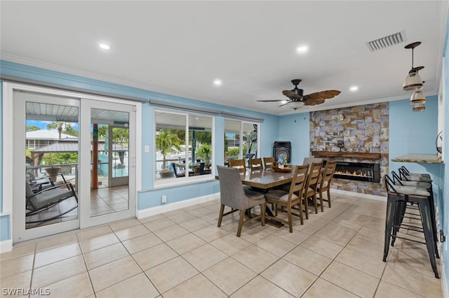 dining area with ceiling fan, french doors, crown molding, a fireplace, and light tile patterned floors