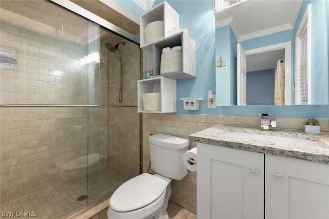 bathroom featuring vanity, a shower with door, toilet, ornamental molding, and tile walls