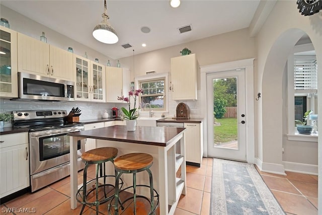 kitchen featuring hanging light fixtures, a center island, light tile patterned floors, and stainless steel appliances