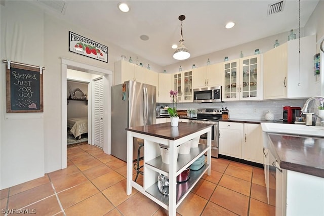 kitchen featuring sink, stainless steel appliances, decorative light fixtures, decorative backsplash, and light tile patterned flooring