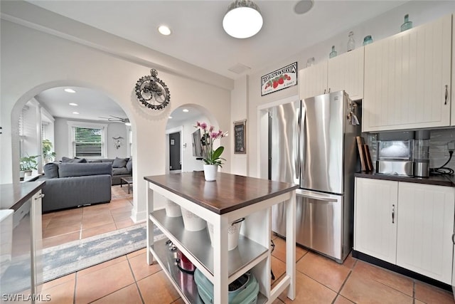 kitchen featuring stainless steel fridge, light tile patterned floors, and ceiling fan