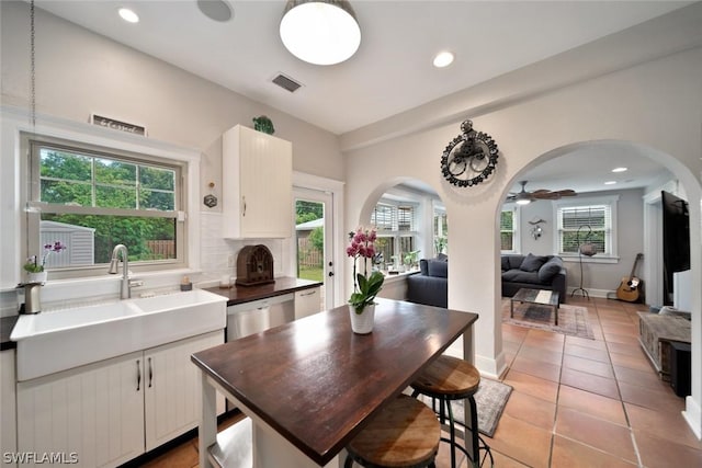 kitchen featuring ceiling fan, sink, light tile patterned floors, tasteful backsplash, and white cabinets