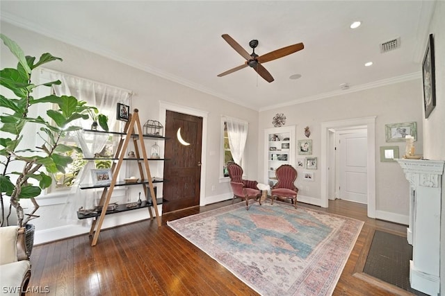 sitting room with ceiling fan, ornamental molding, and dark wood-type flooring