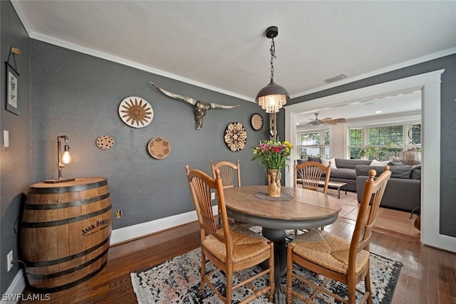 dining area with ceiling fan with notable chandelier, dark hardwood / wood-style flooring, and crown molding