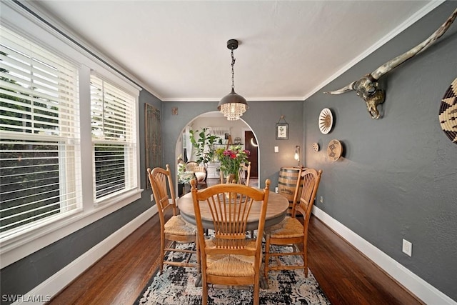 dining space with dark hardwood / wood-style flooring, a chandelier, and ornamental molding