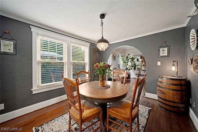 dining area featuring crown molding, dark hardwood / wood-style flooring, and an inviting chandelier