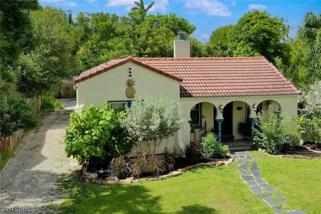 mediterranean / spanish-style home with a front lawn and covered porch