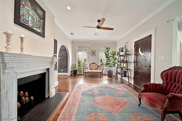 living area with ceiling fan, dark hardwood / wood-style flooring, and crown molding