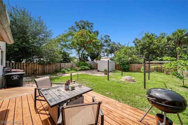 wooden terrace with a storage unit, area for grilling, and an outdoor fire pit