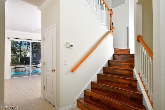 stairway featuring crown molding and tile patterned flooring