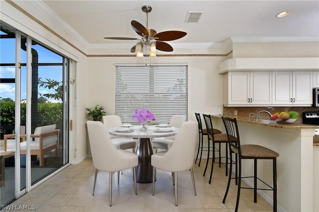 dining area with ceiling fan and crown molding