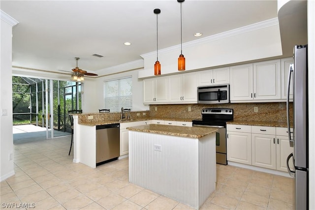 kitchen with kitchen peninsula, appliances with stainless steel finishes, decorative light fixtures, and a kitchen island