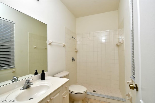 bathroom with tiled shower, tile patterned flooring, vanity, and toilet