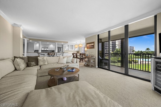 living room featuring floor to ceiling windows, an inviting chandelier, carpet flooring, ornamental molding, and beverage cooler