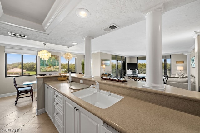 kitchen with sink, light tile patterned floors, crown molding, a chandelier, and white cabinets