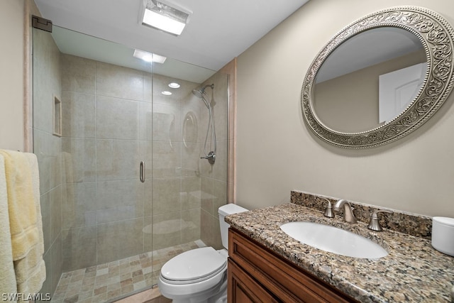 bathroom featuring vanity, toilet, and a shower with shower door