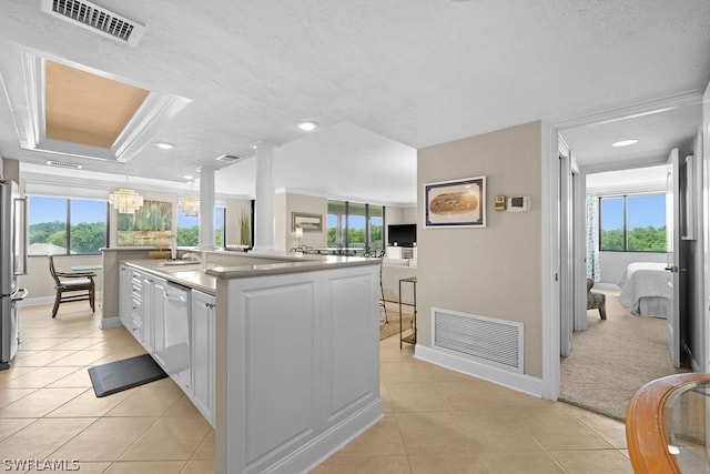 kitchen featuring stainless steel refrigerator, white cabinetry, white dishwasher, a chandelier, and a center island with sink