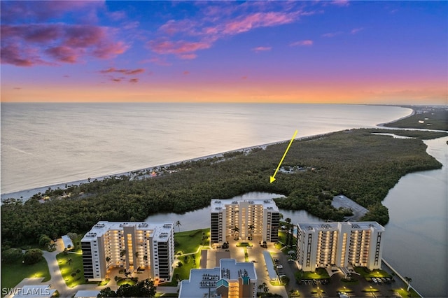 aerial view at dusk with a water view and a view of the beach