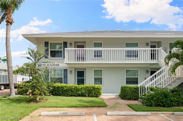 view of front of house featuring a front lawn and a balcony