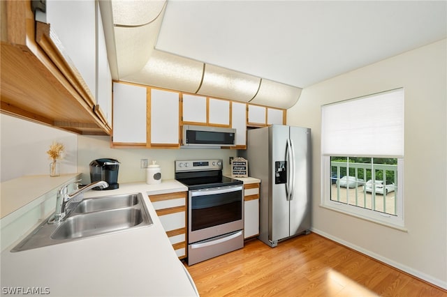 kitchen featuring stainless steel appliances, sink, white cabinetry, and light hardwood / wood-style floors