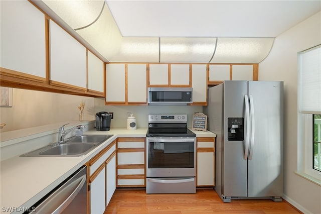 kitchen featuring appliances with stainless steel finishes, light hardwood / wood-style floors, white cabinets, and sink