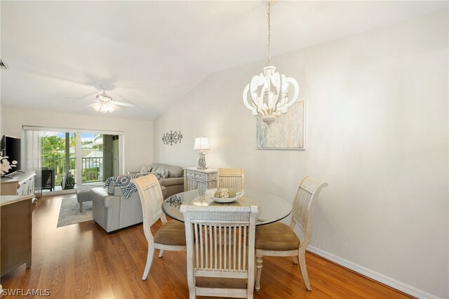 dining room featuring lofted ceiling, ceiling fan with notable chandelier, and hardwood / wood-style flooring