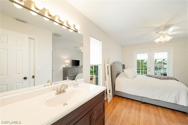 interior space featuring large vanity, wood-type flooring, ceiling fan, and french doors