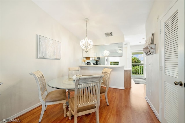 dining space featuring wood-type flooring and an inviting chandelier