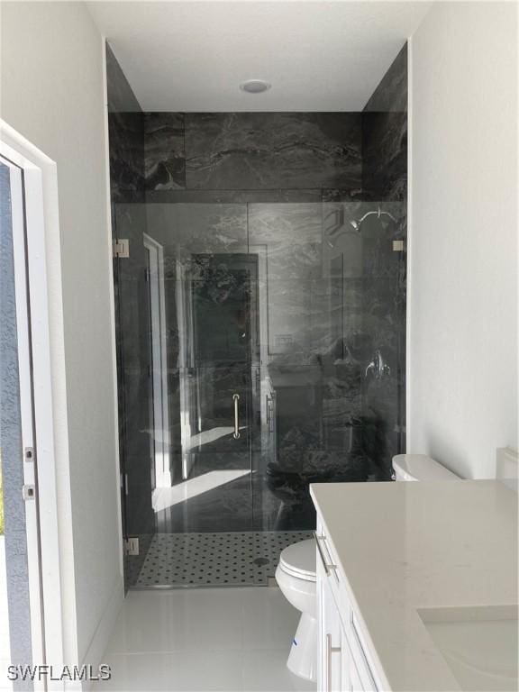 bathroom featuring vanity, a shower with shower door, tile patterned floors, and toilet