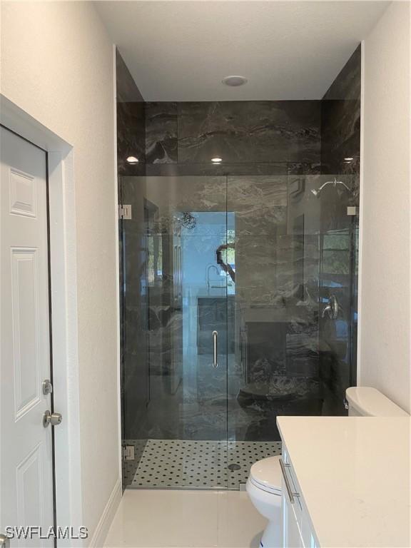 bathroom featuring vanity, tile patterned flooring, a shower with shower door, and toilet