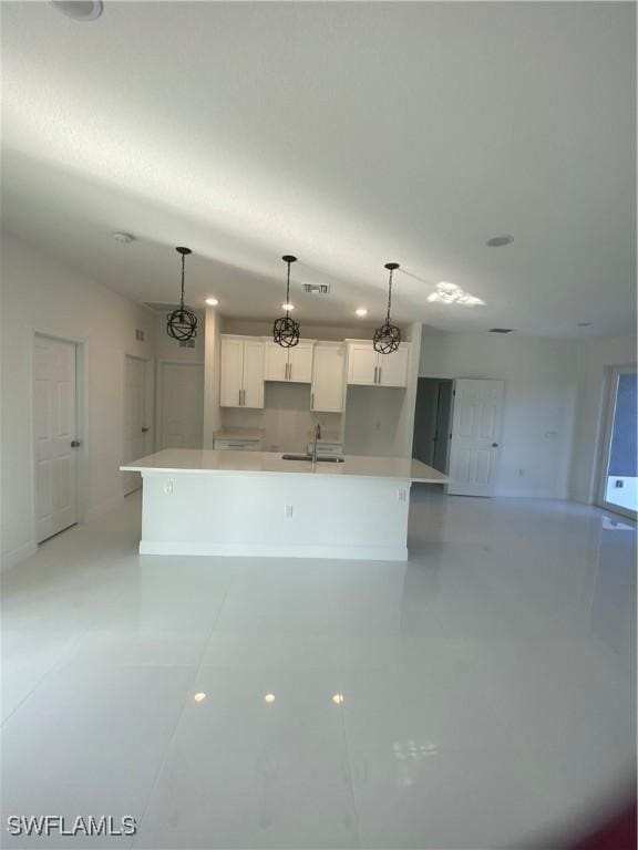 kitchen featuring hanging light fixtures, white cabinetry, a large island, and sink