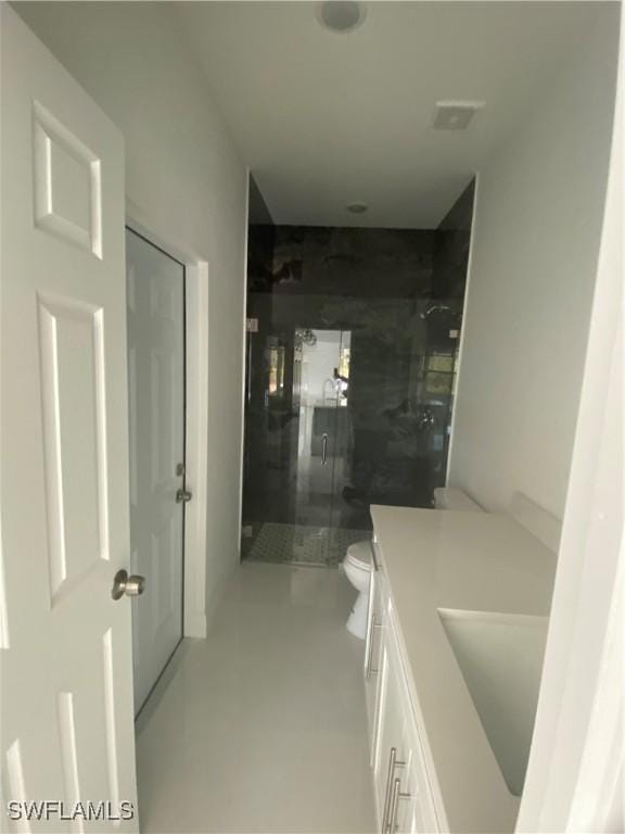 bathroom with walk in shower, vanity, and toilet