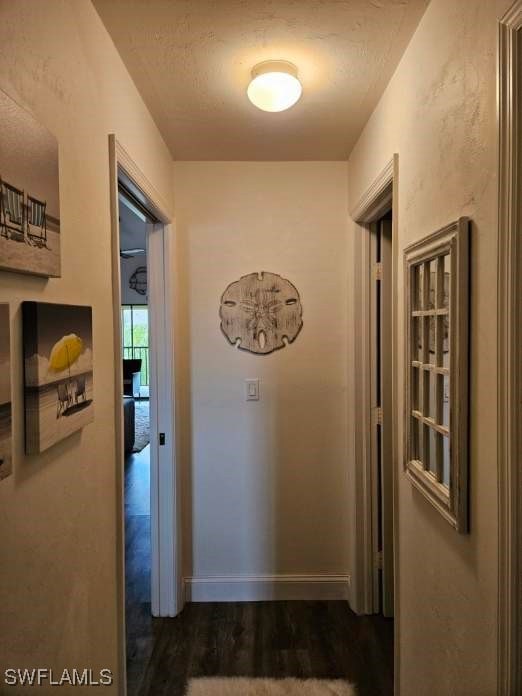 corridor with dark hardwood / wood-style flooring and a textured ceiling