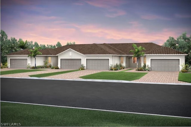 ranch-style house with stucco siding, a front lawn, a tile roof, decorative driveway, and an attached garage