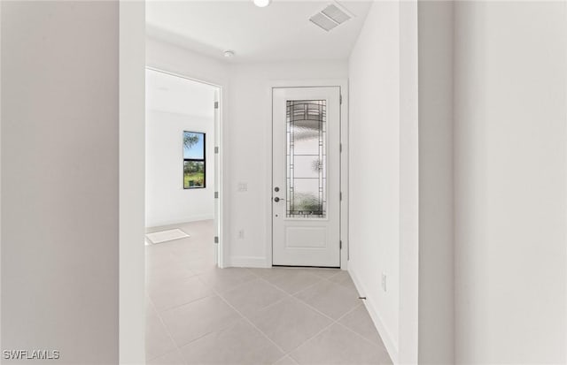 hallway with light tile patterned floors, visible vents, and baseboards