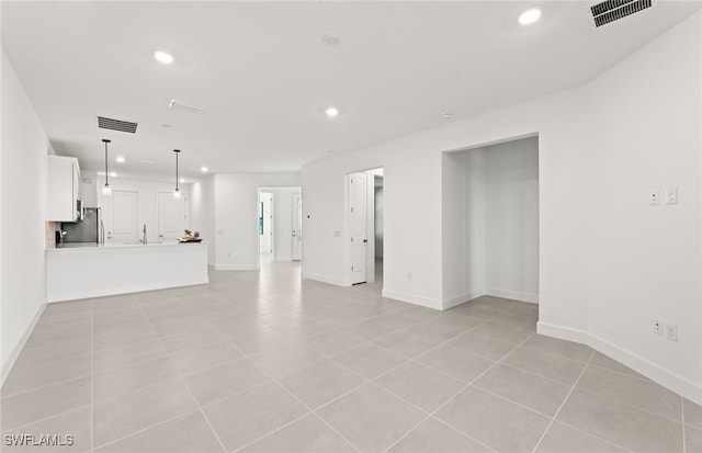 unfurnished living room featuring sink and light tile patterned flooring