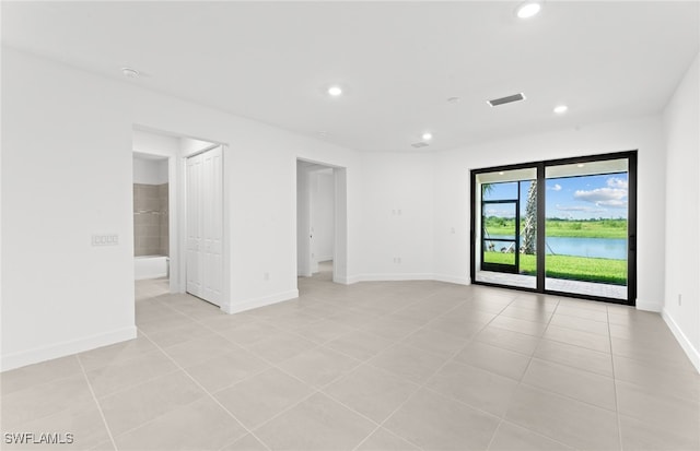 spare room featuring a water view and light tile patterned flooring