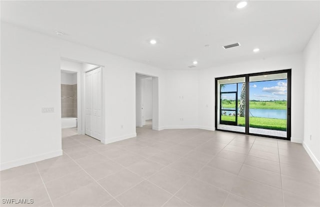 spare room with visible vents, a water view, recessed lighting, light tile patterned floors, and baseboards