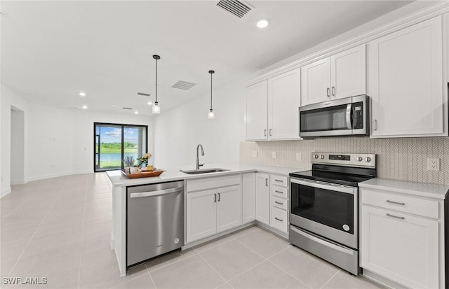 kitchen with visible vents, a peninsula, a sink, decorative backsplash, and stainless steel appliances