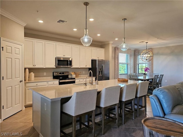 kitchen with decorative light fixtures, white cabinetry, an island with sink, and appliances with stainless steel finishes