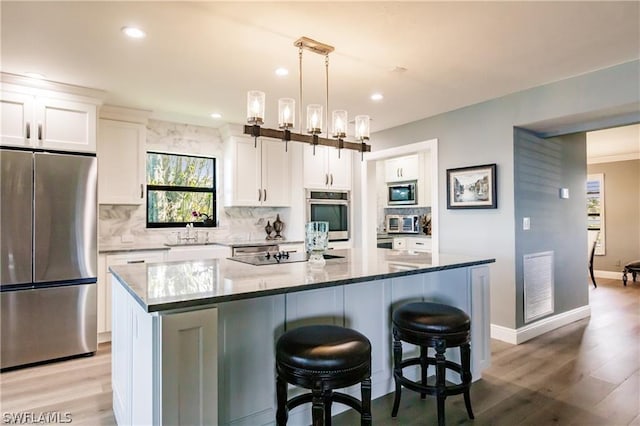 kitchen featuring white cabinets, appliances with stainless steel finishes, a center island, and pendant lighting