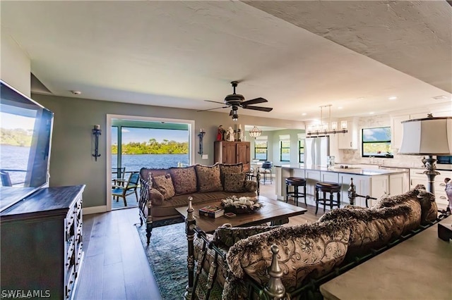 living room with a healthy amount of sunlight, ceiling fan with notable chandelier, and hardwood / wood-style flooring