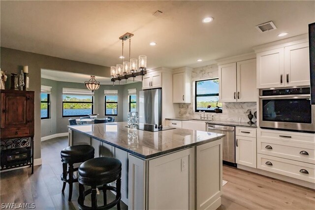 kitchen featuring white cabinets, a center island, stainless steel appliances, and a wealth of natural light